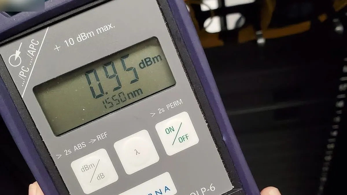 Handheld optical power meter showing 0.95 dBm at 1550 nm, with dBm/dB and wavelength buttons